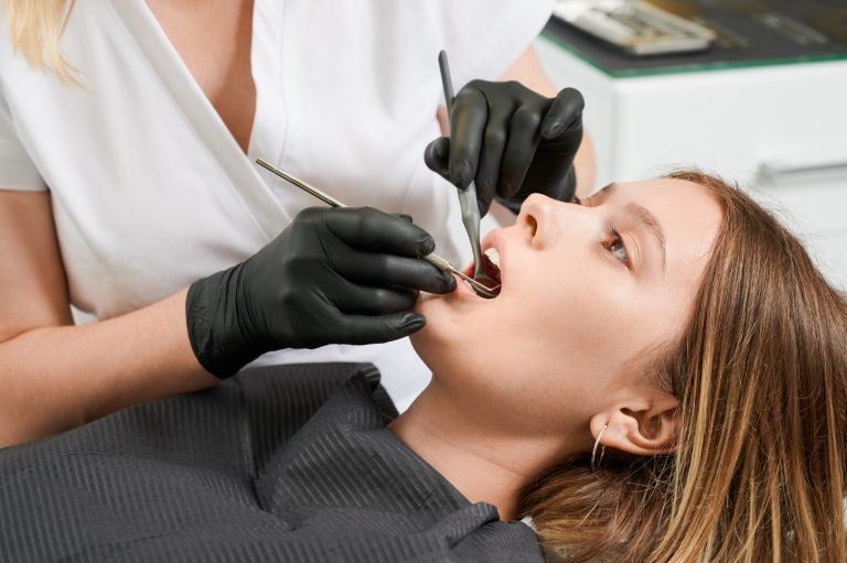 Female doctor examining patient teeth in dental clinic.