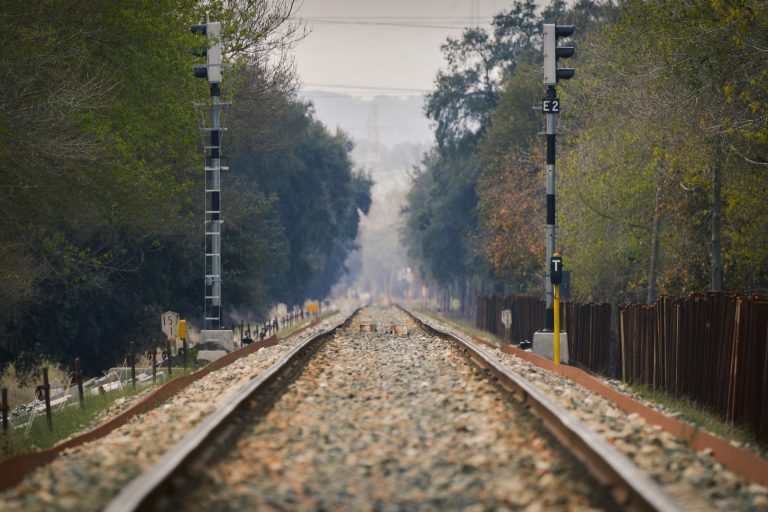 Closeup of train rails and a wooden fence on the right